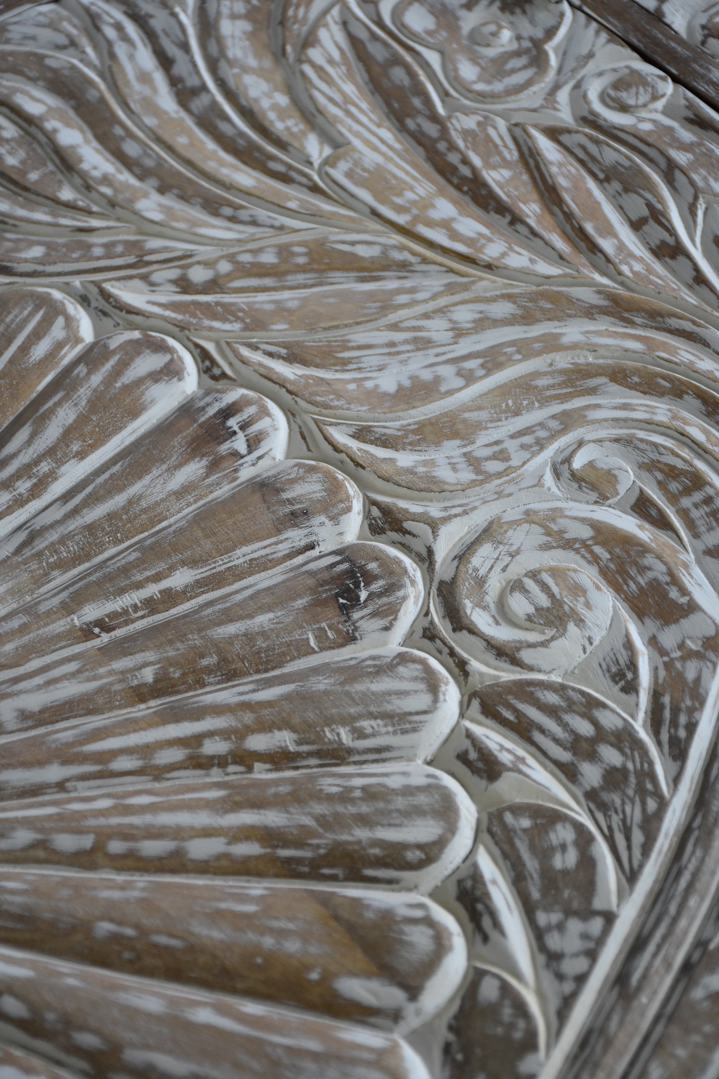 Textured wooden surface of a media cabinet with artistic carvings.